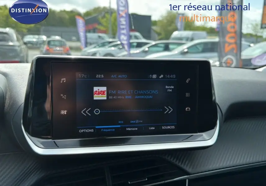 Écran tactile central de la Peugeot 2008 noir perle métal, affichant la radio FM avec interface moderne et finition carbone.