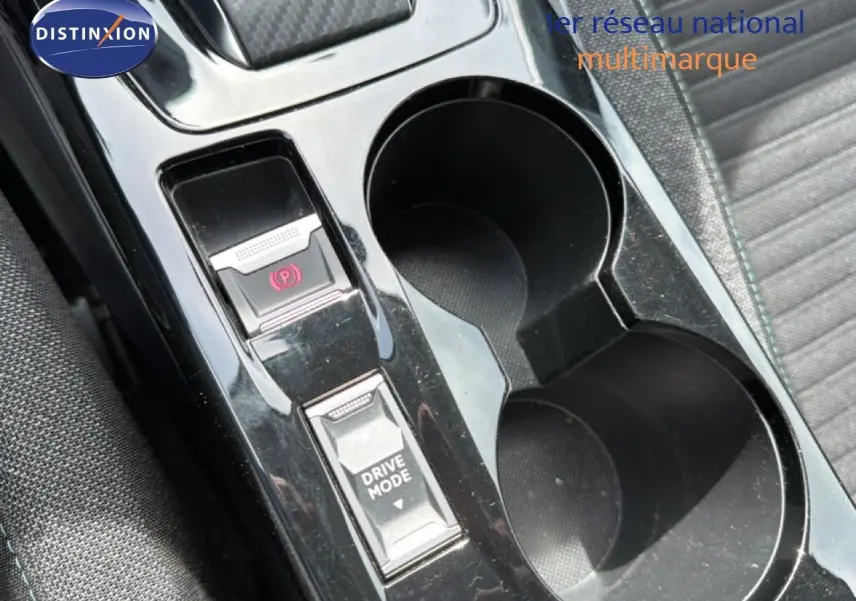 Gros plan sur la console centrale noire perle métal du Peugeot 2008, avec boutons frein à main électrique et mode de conduite.