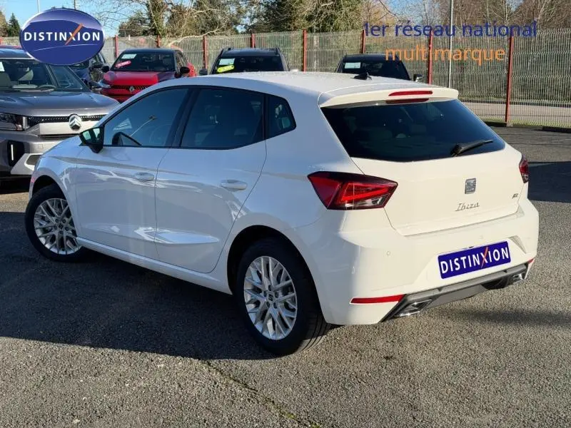 SEAT Ibiza 1.0 TSI 115cv FR blanc Nevada métallisé vue 3/4 arrière droit sur parking extérieur.