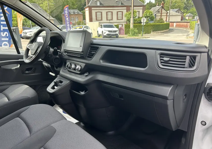 Vue intérieure côté passager du Renault Trafic Fourgon blanc Glacier 2025, avec tableau de bord et écran tactile central.