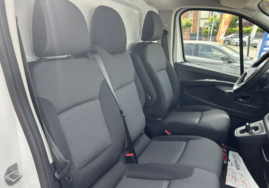 Vue intérieure côté conducteur du Renault Trafic Fourgon blanc glacier, montrant la banquette passager 2 places en tissu gris.