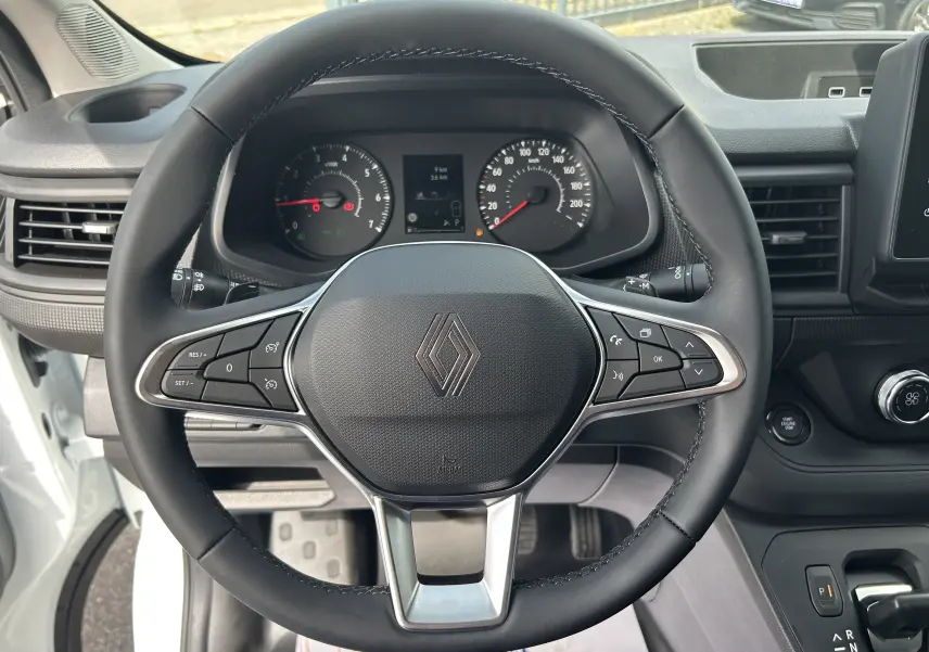 Vue rapprochée du volant noir de Renault Trafic Fourgon 2025 avec tableau de bord et commandes visibles.