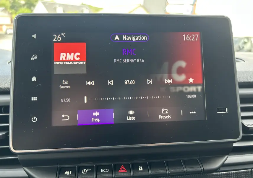 Écran tactile central du Renault Trafic L1H1 2025 affichant la radio RMC à 87.6 FM, avec commandes en bas.