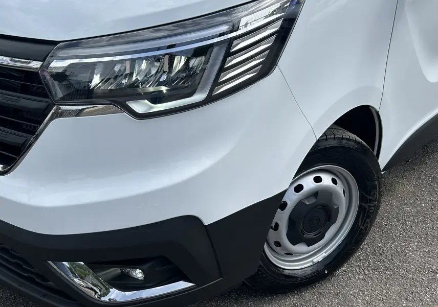 Gros plan sur l'avant droit blanc glacier du Renault Trafic Fourgon avec phare LED et jante acier noire.