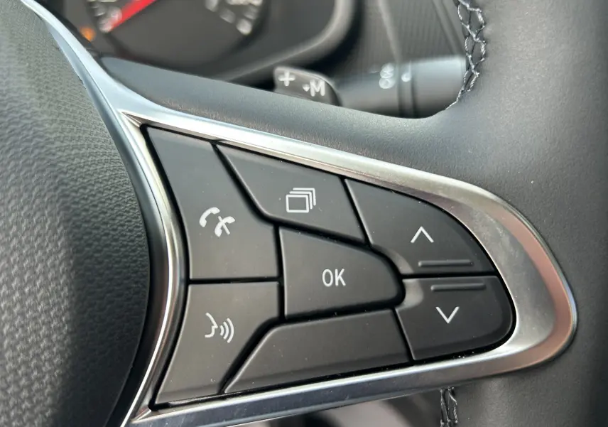 Gros plan sur les commandes multifonctions noires du volant du Renault Trafic Fourgon 2025, avec finition argentée.