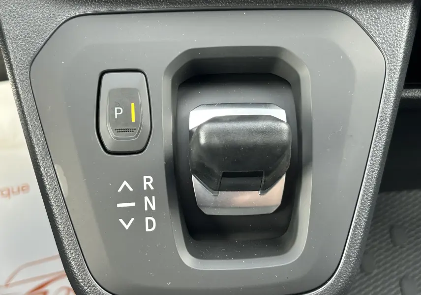Gros plan sur le levier de vitesses automatique noir et gris du Renault Trafic Fourgon blanc Glacier, avec bouton parking éclairé.