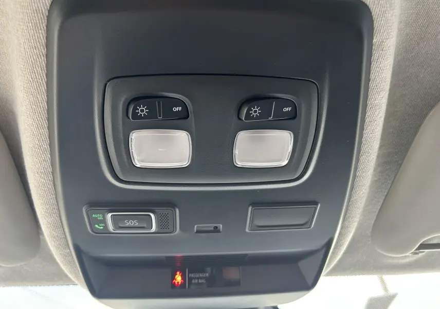 Gros plan sur la console de plafonnier noir avec commandes d’éclairage et bouton SOS du Renault Trafic Fourgon blanc.