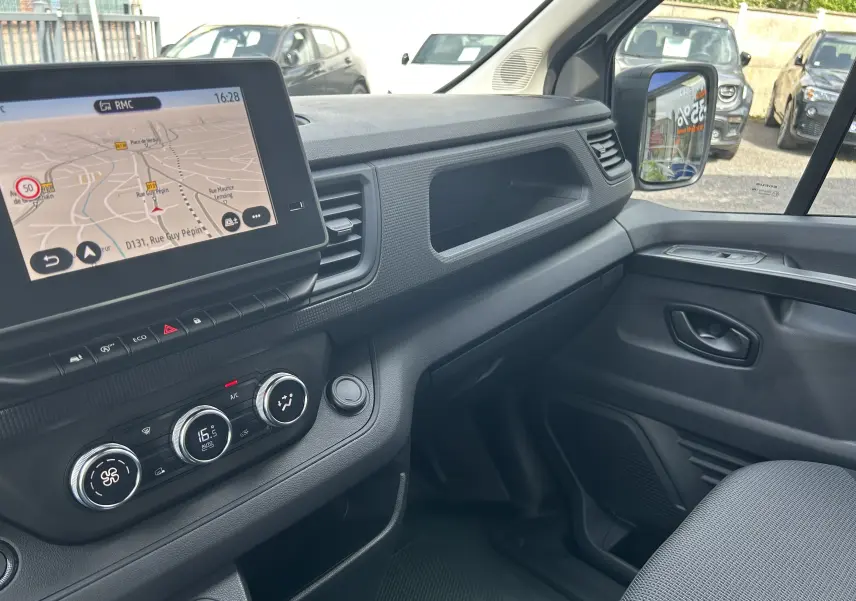 Vue intérieure côté passager du Renault Trafic Fourgon 2025, avec écran tactile Easy Link et commandes de climatisation.