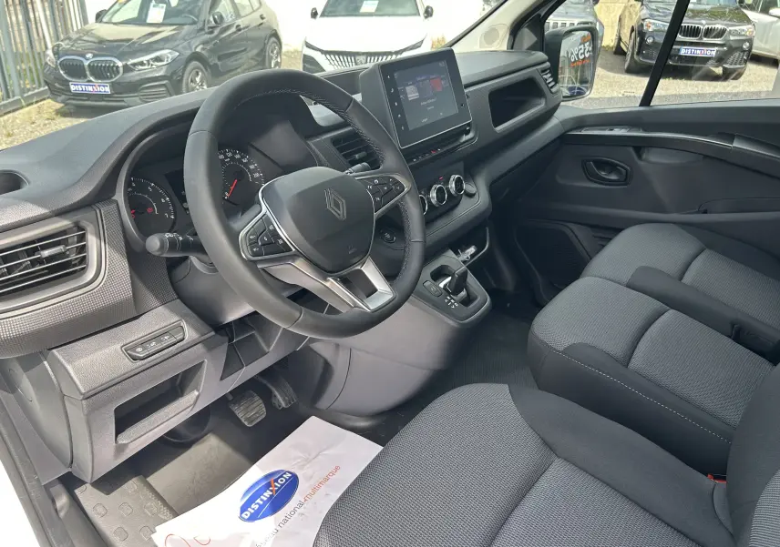 Vue intérieure côté conducteur du Renault Trafic Fourgon 2025, volant multifonction et écran tactile central visibles.