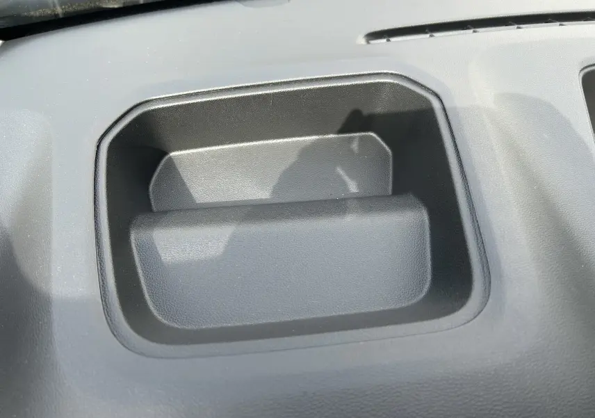 Gros plan sur un rangement intégré au tableau de bord du Renault Trafic Fourgon blanc Glacier, intérieur gris.