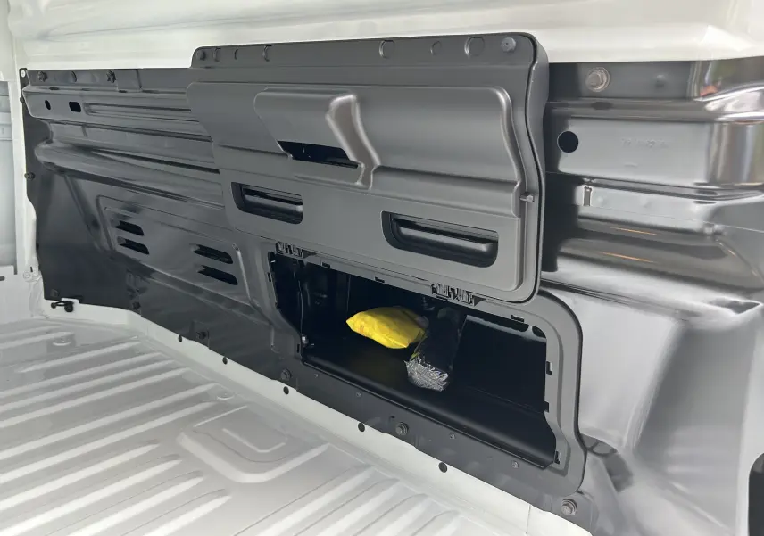 Détail de la cloison complète tôlée côté intérieur du Renault Trafic Fourgon blanc glacier, avec trappe ouverte et rangement visible.