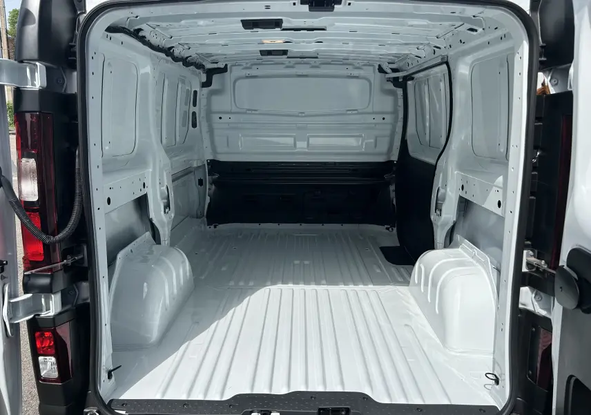 Vue arrière intérieure du Renault Trafic Fourgon blanc glacier, montrant l’espace de chargement vide et tôlé.