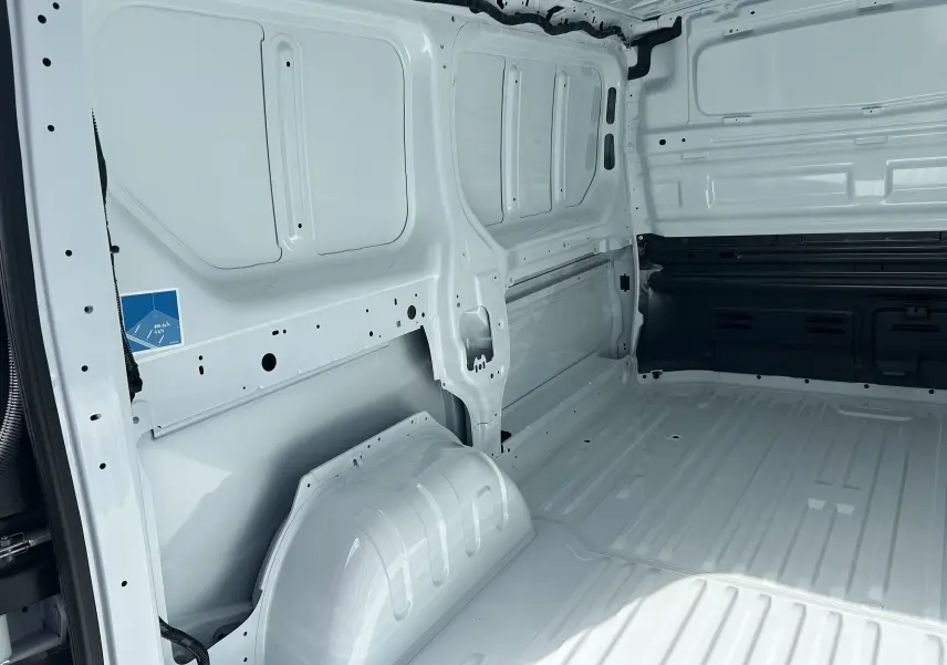 Intérieur du fourgon Renault Trafic L1H1 blanc glacier, vue sur la zone de chargement vide avec cloison tôlée partielle.