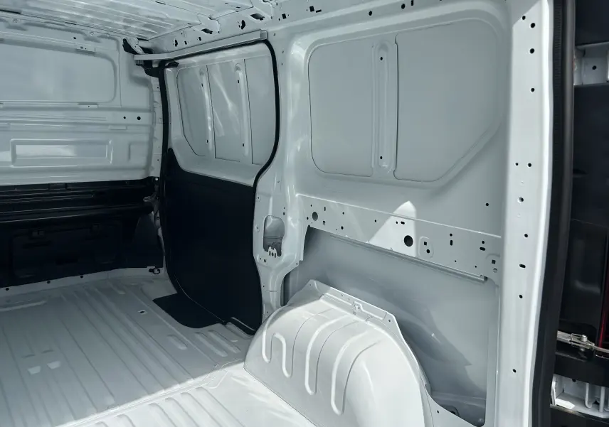 Intérieur du fourgon Renault Trafic L1H1 blanc glacier, vue latérale droite montrant la cloison tôlée et l'espace de chargement vide.