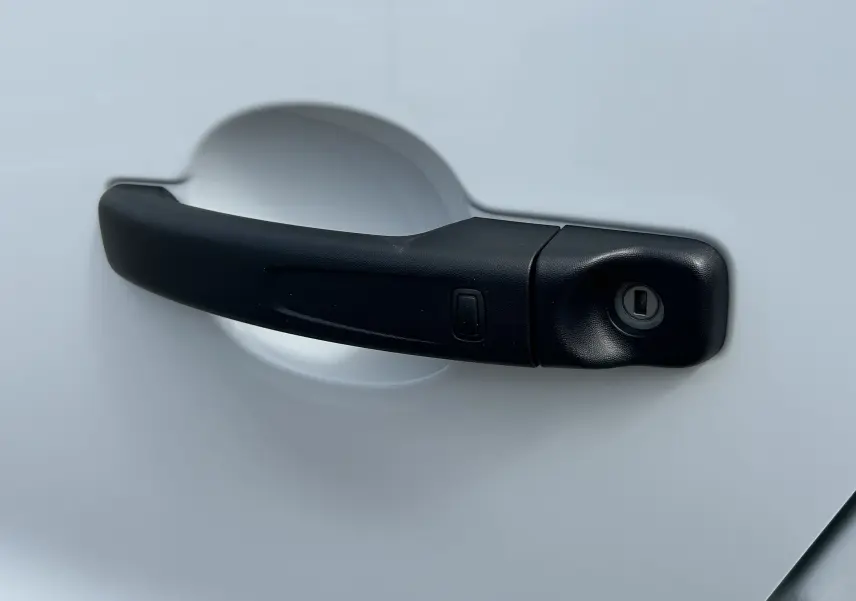 Poignée de porte noire en gros plan sur la portière blanche glacier du Renault Trafic Fourgon L1H1 2025.