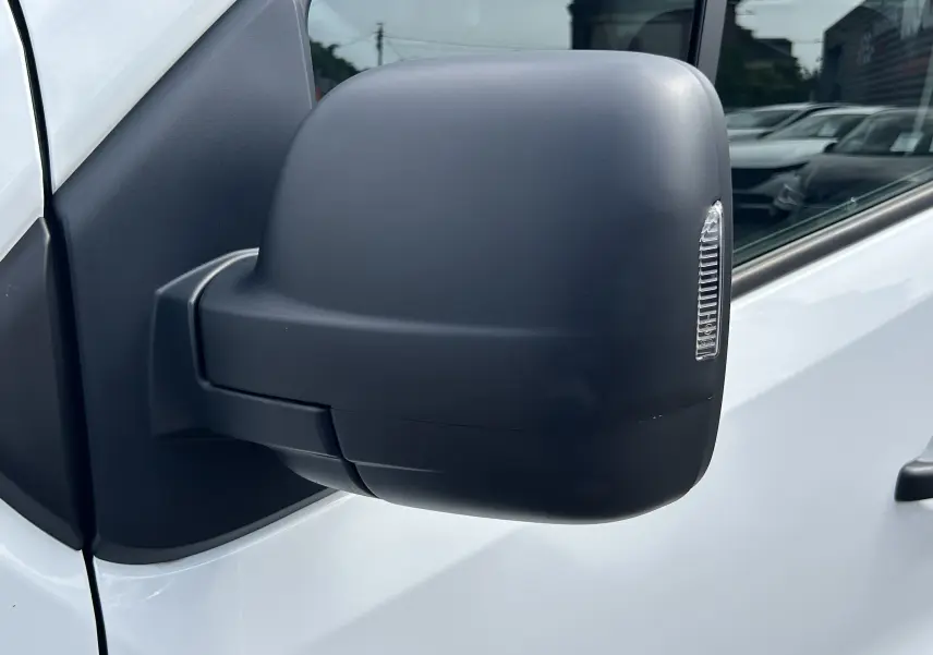 Gros plan sur le rétroviseur droit noir du Renault Trafic Fourgon blanc glacier, avec clignotant intégré.