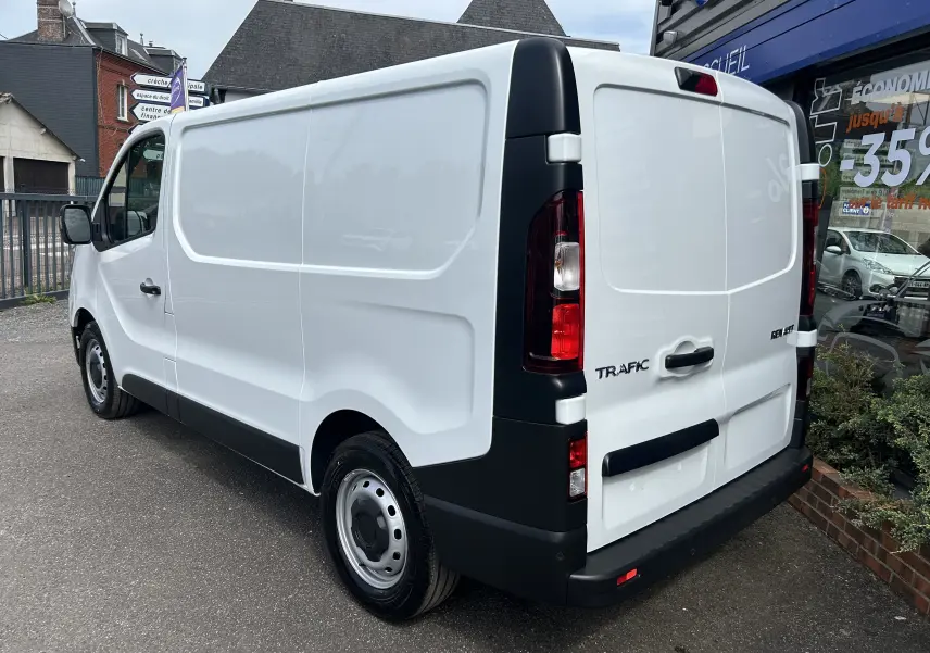Vue 3/4 arrière droite du Renault Trafic Fourgon blanc Glacier avec portes arrière fermées et feux verticaux noirs.