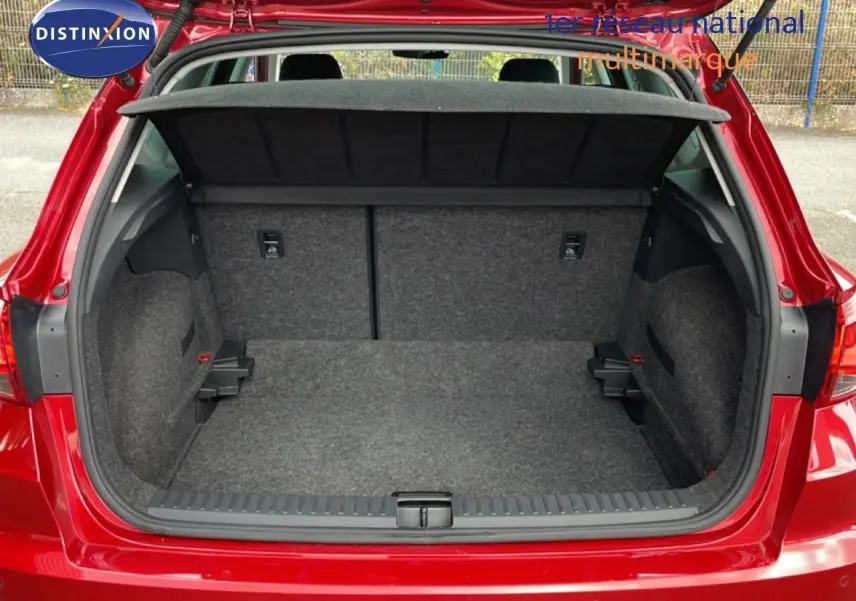 Coffre ouvert d’un SEAT Arona rouge Désir Métal, vue arrière montrant l’espace de chargement et la plage arrière noire.