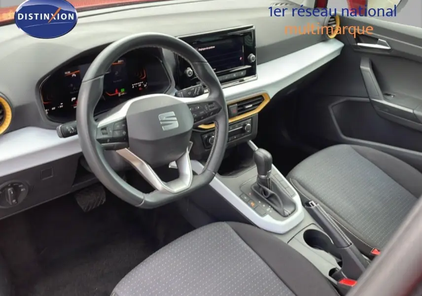 Vue intérieure côté conducteur du SEAT Arona 2025, volant cuir multifonction et sellerie tissu noire avec console centrale grise.