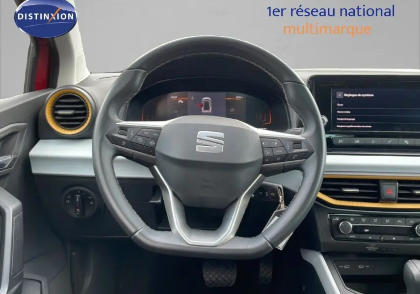 Vue intérieure centrée sur le volant noir du SEAT Arona 2025 avec tableau de bord digital et détails jaunes autour des aérateurs.