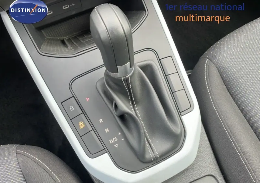 Gros plan sur la console centrale et levier de vitesse automatique en cuir noir du SEAT Arona 2025, intérieur tissu gris.