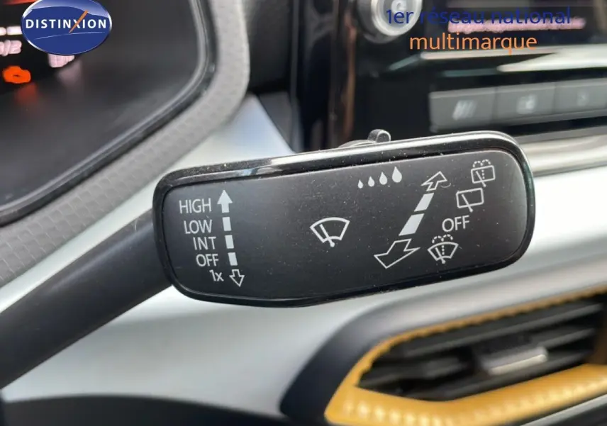 Gros plan sur la commande des essuie-glaces dans l’habitacle du SEAT Arona 2025, intérieur noir avec surpiqûres jaunes.