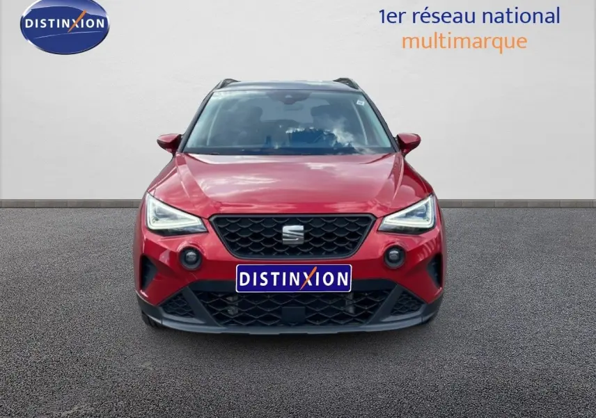 Vue avant d'un SEAT Arona rouge Désir Métal avec toit noir, calandre noire et phares LED allumés.