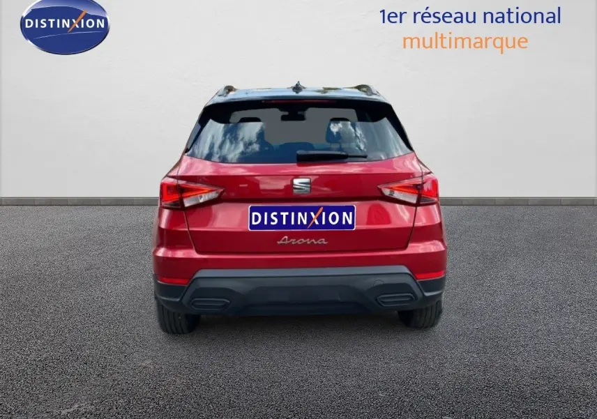 Vue arrière d'un SEAT Arona rouge Désir Métal avec toit noir, stationné devant un mur blanc.