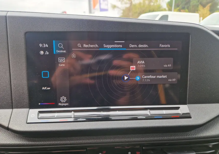 Écran tactile central du Volkswagen Caddy Cargo blanc 2023 affichant le menu de navigation avec suggestions de destinations.
