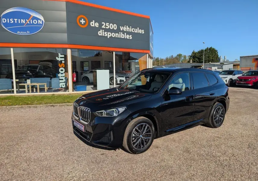 BMW X1 XDrive 20d noir métallisé en 3/4 avant droit, avec jantes alliage et calandre chromée M Sport visible.