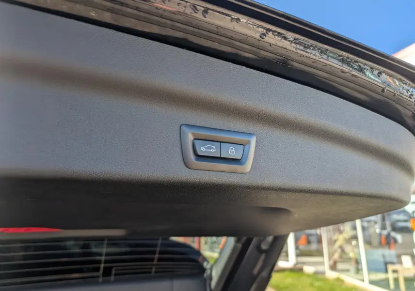 Bouton de fermeture électrique du hayon sur la partie intérieure du coffre d’un BMW X1 noir.