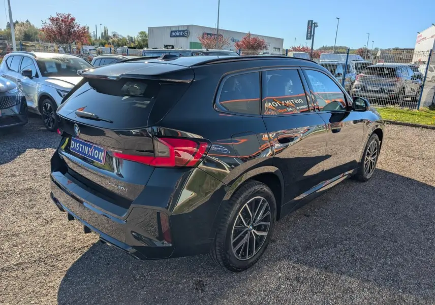 BMW X1 XDrive 20d noir vue 3/4 arrière droit, jantes alliage bicolores et vitres teintées.