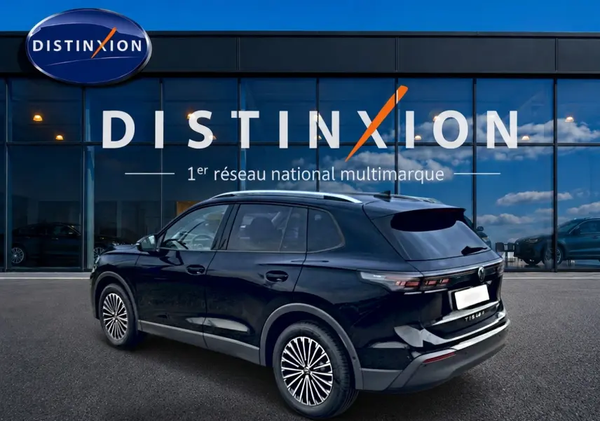 Volkswagen Tiguan 1.5 eTSI noir vue 3/4 arrière droit avec barres de toit argentées devant un showroom Distinxion.
