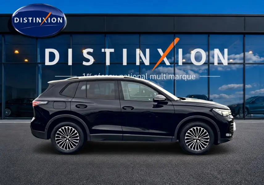 Volkswagen Tiguan noir en profil droit devant une vitrine avec logo Distinxion, jantes stylisées visibles.