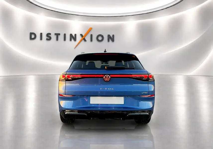 Vue arrière d'un Volkswagen T-Roc bleu céleste 2026 avec feux LED reliés et logo central lumineux.