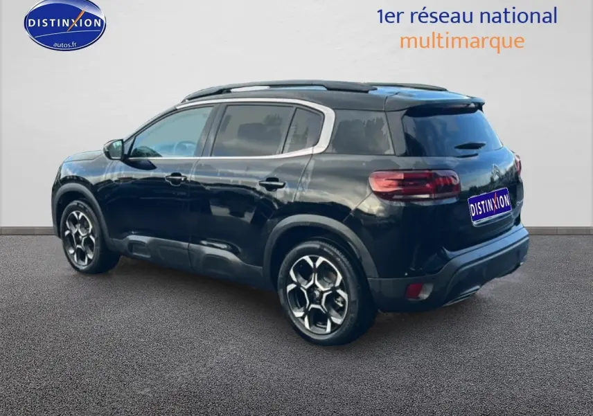 Vue 3/4 arrière droite d'un Citroën C5 Aircross noir avec barres de toit et jantes alliage distinctives.