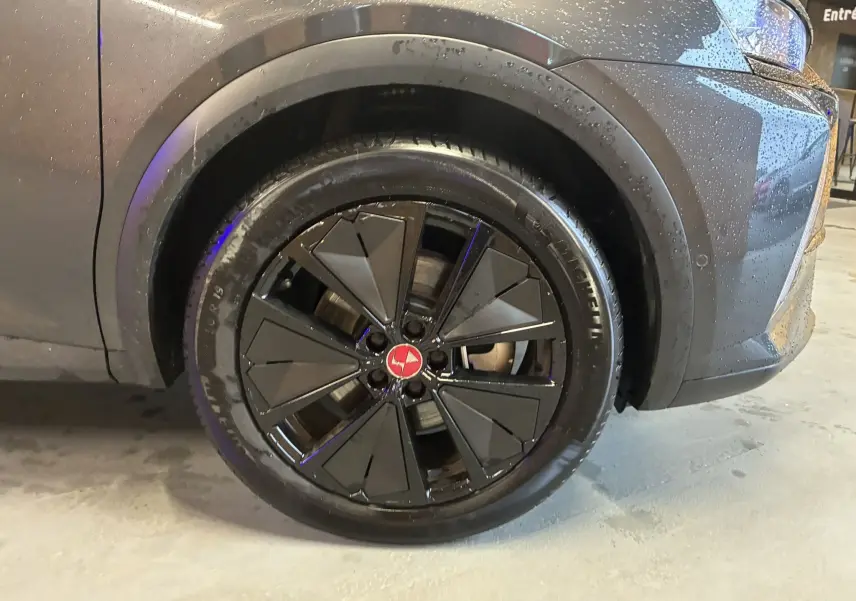 Gros plan sur la roue avant droite du DS7 E-TENSE gris 2024 avec jante noire au design géométrique et logo rouge central.