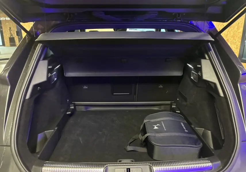 Vue arrière du coffre ouvert du DS7 E-TENSE gris 2024, avec sac de chargeur hybride visible à droite.