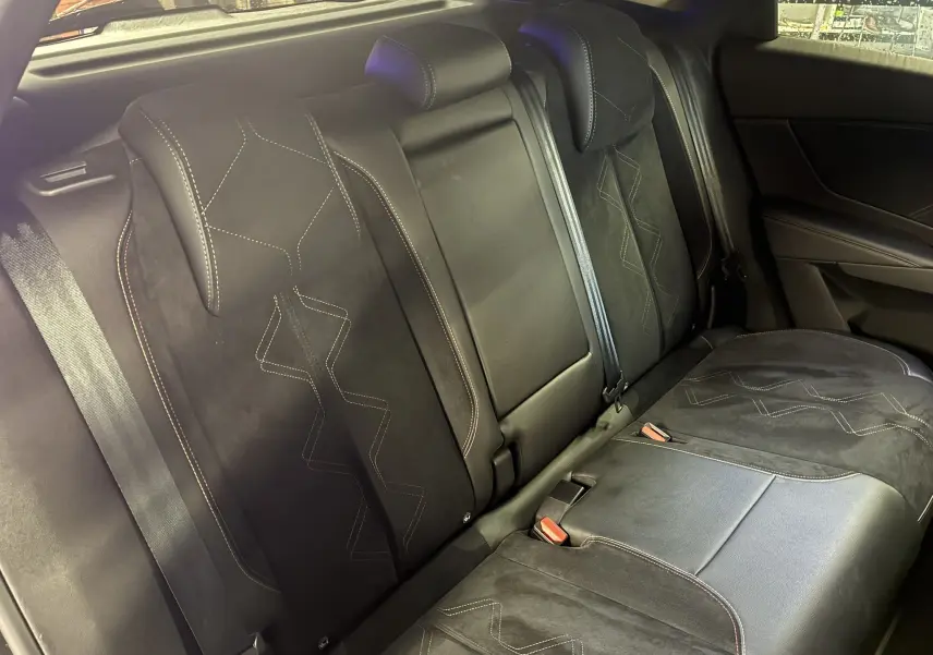 Vue intérieure des sièges arrière noirs en cuir et alcantara du DS7 E-TENSE 2024, avec surpiqûres décoratives visibles.