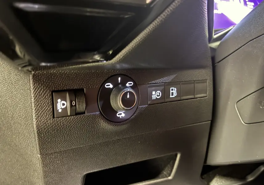 Gros plan sur les commandes d'éclairage et de carburant à gauche du volant dans l'habitacle noir du DS7 E-TENSE gris 2024.