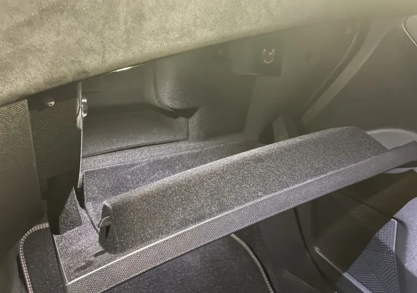 Gros plan sur la boîte à gants ouverte de la DS7 E-TENSE 2024, intérieur noir avec finition texturée.