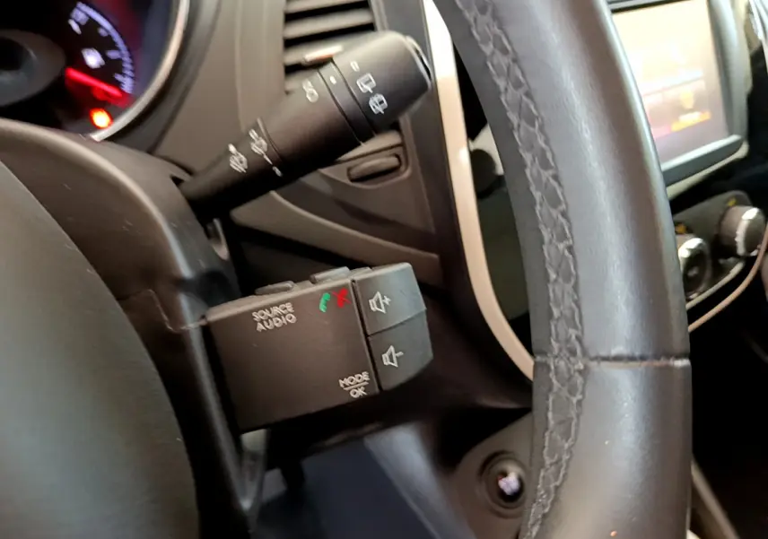 Gros plan sur le volant cuir noir et les commandes audio au volant du Renault Captur Business gris foncé, vue intérieure côté gauche.