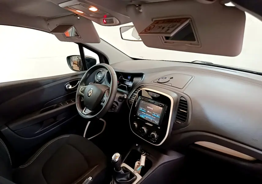 Vue intérieure côté conducteur du Renault Captur gris foncé, volant cuir multifonctions et écran tactile central allumé.