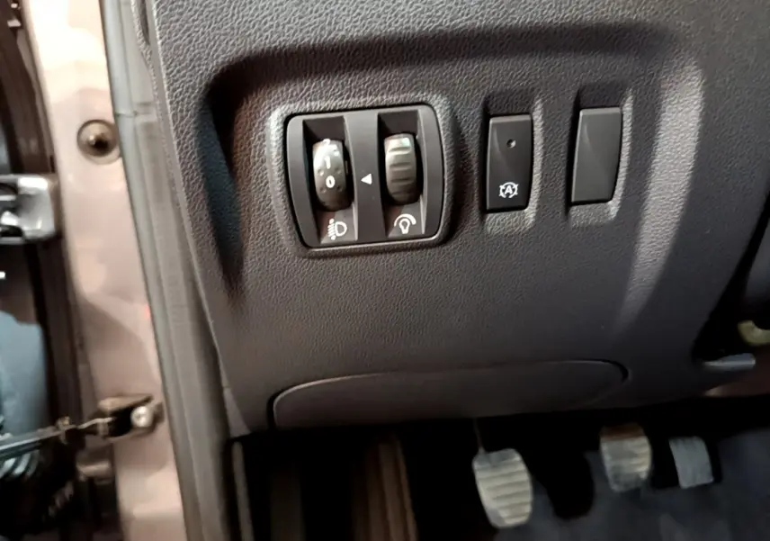 Détail des commandes de réglage des phares et bouton stop-start côté gauche du tableau de bord d’un Renault Captur gris foncé 2018.