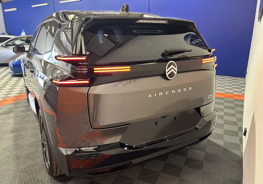 Vue 3/4 arrière droite du Citroën C5 Aircross gris Platinium avec feux arrière LED allumés et toit noir biton.