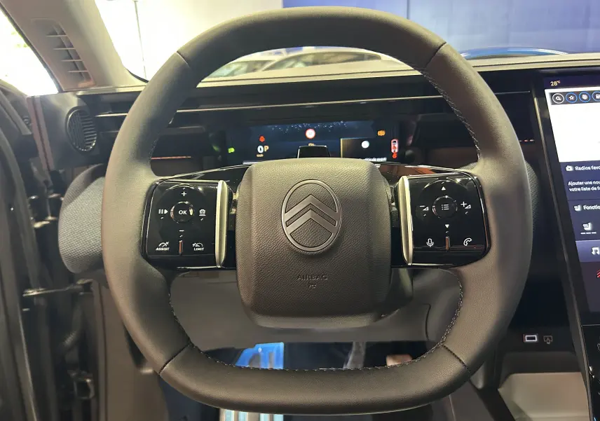 Vue rapprochée du volant noir du Citroën C5 Aircross II Max Hybrid avec commandes tactiles intégrées.