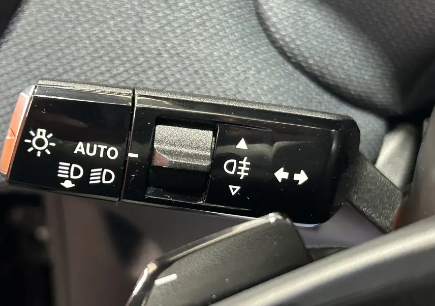 Gros plan sur la commande des feux et clignotants du Citroën C5 Aircross II Max Hybrid 145, intérieur noir.