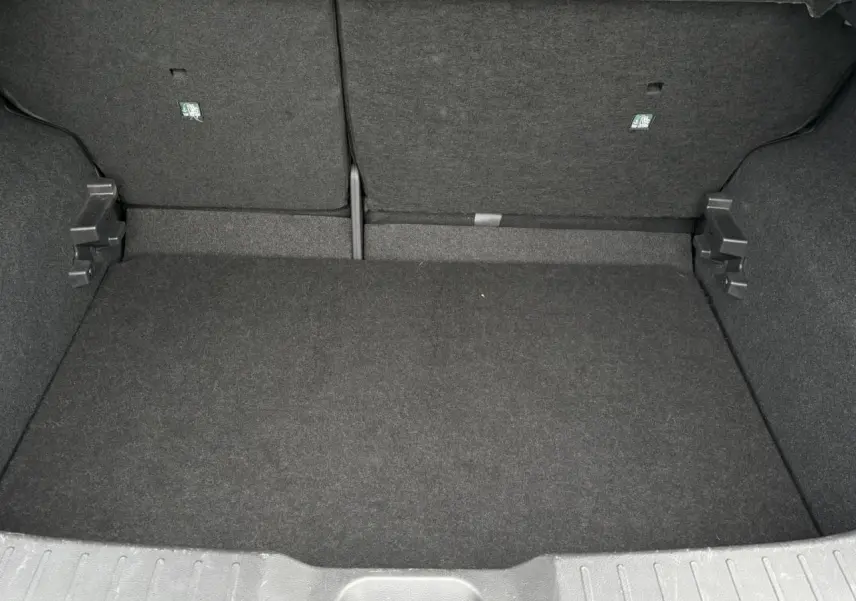 Coffre spacieux et vide du Nissan Juke blanc perle 2024, vue intérieure arrière avec revêtement noir.