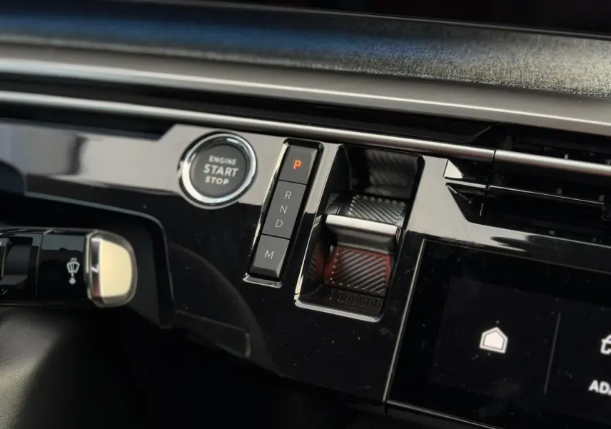 Gros plan sur la console centrale noire brillante du Peugeot 3008 Hybrid avec bouton start/stop et commandes de boîte auto.