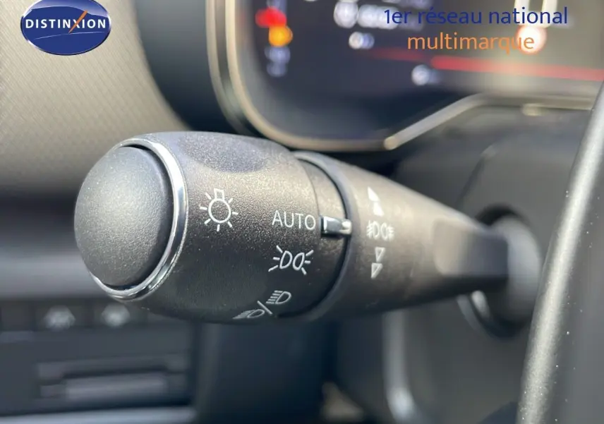 Gros plan sur la commande des phares du Citroën C5 Aircross 2025, intérieur noir avec affichage digital flou.